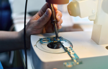 technician repairing the smartphone's motherboard in the lab with copy space. the concept of...