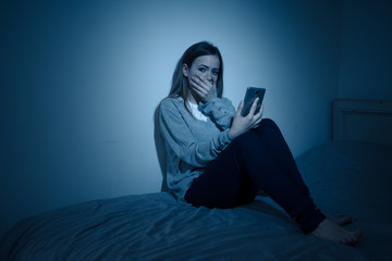 Naklejka premium Depressed teenager girl on mobile phone victim of cyberbullying feeling sad, unhappy and lonely