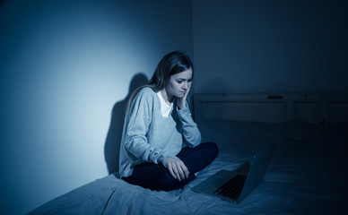 Sad teenager girl with laptop suffering bullying and harassment online. Cyberbullying concept.