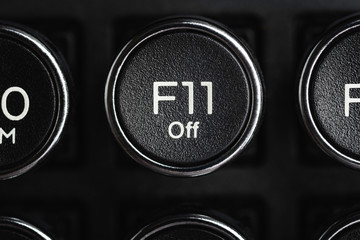 A close-up or macro shot of the round F11 key of a black antique style typewriter keyboard in horizontal image format.