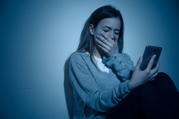 Depressed teenager girl on mobile phone victim of cyberbullying feeling sad, unhappy and lonely