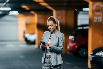 Business, technology and transportation concept. Elegant businesswoman using phone in underground...