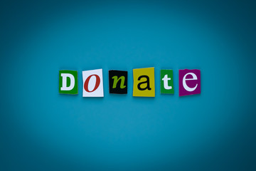 Word donate of cut letters on blue background. Donation concept. Headline - donate. A word writing...