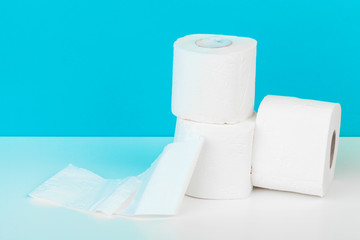 Three toilet paper rolls isolated on white table with blue background