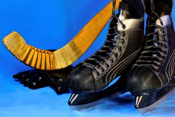 Fototapeta na wymiar Ice skates for training on ice and a hockey stick with a ball. Skates are used for movement on a flat solid ice surface. Skates are sports or walking equipment, consists of boots and metal blades atta