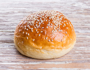 bun with sesame seeds on wooden background