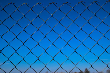 Fototapeta premium Metal mesh fence against a blue sky