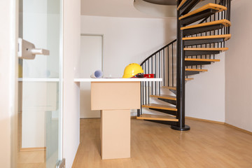Provisorischer Planungstisch mit Bauplan und Helm in einer leeren Maisonette Wohnung