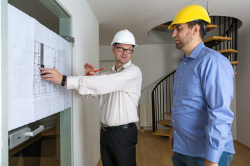 Der Architekt erklärt dem Bauherren Details des Bauplans und zeigt ihm die Planbereiche