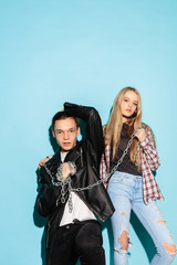 Fototapeta na wymiar Bad games. Close up fashion portrait of two young cool hipster girl and boy wearing jeans wear. Studio shot of two cheerful best friends having fun and making serious faces.