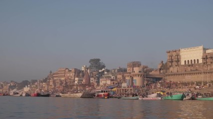 The holy city of Varanasi, oldest Indian living town, as seen from the sacred river Ganges at day break sunrise of the beautiful architecture of temples and ghats with pilgrims and tourists 