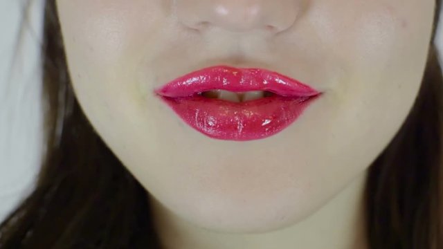 Sexy female lips of bright color. The girl licks her lips. She has a tongue piercing.