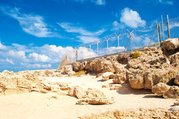 Military fence from barbed wire on a barren terrain