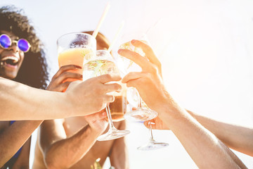 Group of happy friends cheering with tropical cocktails at boat party - Young people having fun in caribbean sea tour - Youth and summer vacation concept - Focus on close-up hands glass