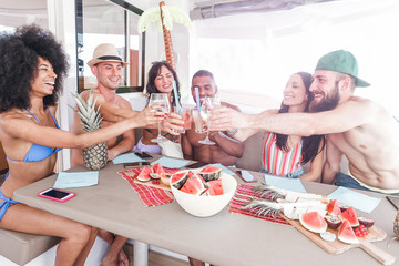 Happy friends cheering with tropical cocktails in patio boat party - Young people having fun in summer vacation - Youth lifestyle, friendship and holiday concept - Main focus on hands glasses