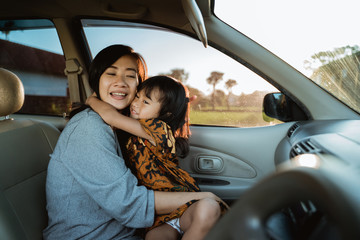 happy child and mother embrace each other while going with the car