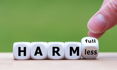 Hand turns a dice and changes the expression "harmful" to "harmless".