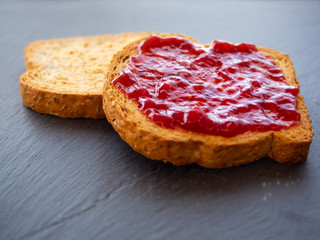 Two slices of toast with raspberry jam on a slate plate