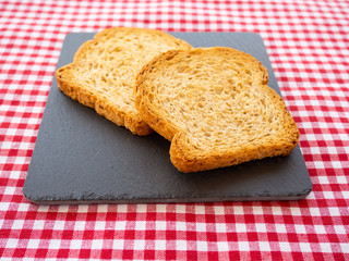 Two slices of toast on a slate plate and tablecloth vintage style