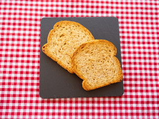Two slices of toast on a slate plate and tablecloth vintage style
