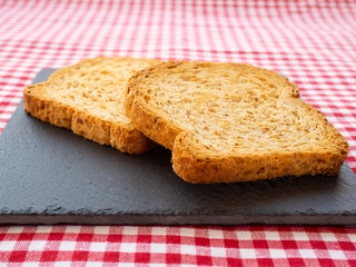 Two slices of toast on a slate plate and tablecloth vintage style