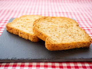 Two slices of toast on a slate plate and tablecloth vintage style