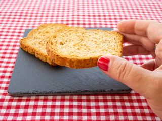 A woman with nails painted red with a rusk in her hand