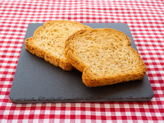 Two slices of toast on a slate plate and tablecloth vintage style