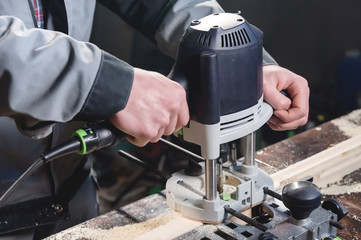Close-up electric milling cutter in the hands of a worker in a home workshop. Starting a business. Craftsman