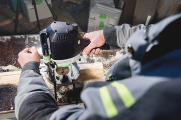Close-up electric milling cutter in the hands of a worker in a home workshop. Starting a business. Craftsman