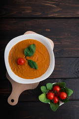 Pumpkin and carrot cream soup with  parsley in  a white bowl on dark wooden background. Rustic, food.