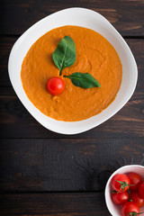 Pumpkin and carrot cream soup with  parsley in  a white bowl on dark wooden background. Rustic, food.