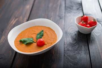 Pumpkin and carrot cream soup with  parsley in  a white bowl on dark wooden background. Rustic, food.