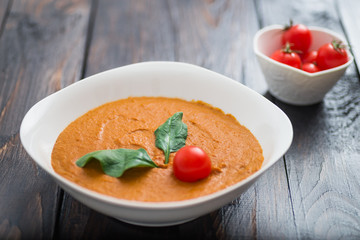 Pumpkin and carrot cream soup with  parsley in  a white bowl on dark wooden background. Rustic, food.