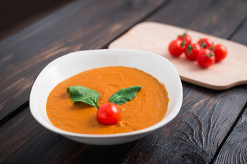 Pumpkin and carrot cream soup with  parsley in  a white bowl on dark wooden background. Rustic, food.