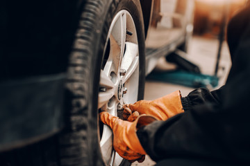 Close up of auto mechanic changing tire in workshop.