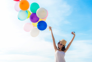 Smiling lifestyle asian woman chill hand holding balloon on the beach. Relax and Enjoy in summer holiday. Summer and Travel Concept