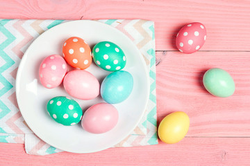 Easter eggs on the plate on pink wooden table.