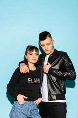 Fototapeta premium We are friends. Close up fashion portrait of two young cool hipster girl and boy wearing jeans wear. Studio shot of two models having fun and making serious faces.