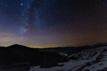 The night sky with millions of stars and galaxies overlooking the Carpathian peaks, spruce and...