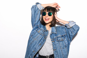 Pretty young sexy fashion woman posing on white wall background dressed in hipster style jeans outfit. Stylish fashionable blonde girl hipster in black clothes.