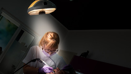 Female dentist with dental tools checking up patient teeth