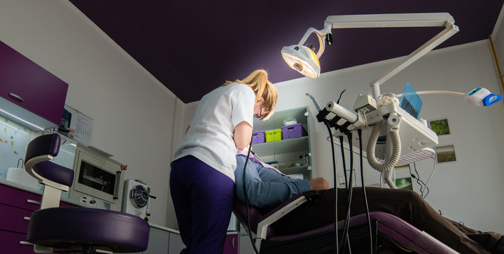Female dentist with dental tools checking up patient teeth