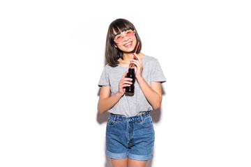 portrait of beautiful crazy smiling brunette woman drinking soda from bottle with straw in casual summer clothes with no makeup isolated on white