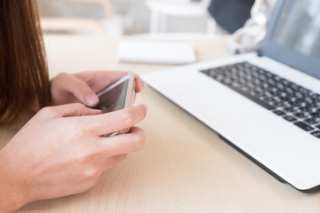 Woman use smartphone - working freelance in the coffee shop with laptop on desk
