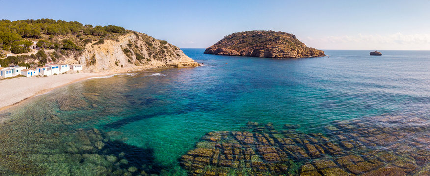 Panoramic view of Portitxol Barraca beach in Javea, Spain, with some typical white and blue mediterranean houses
