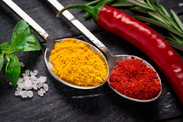 Turmeric and red hot pepper on spoon on dark wooden background. Spices of Indian cuisine