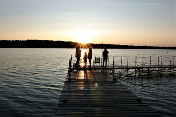 Grandfather and grandchildren enjoying a beautiful sunset at a lake, angling