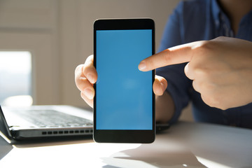 Woman using smartphone. Woman pointing on smartphone. Blue screen. Close Up