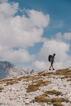 A young man hiking with a backpack upon a peak in Europe in the summer.